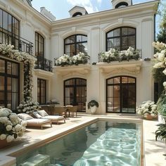 an outdoor swimming pool in front of a large white building with lots of windows and doors