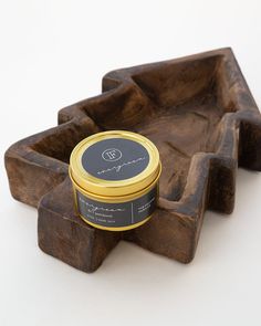 a wooden tray with a candle on it and a small container in the middle that has a black lid