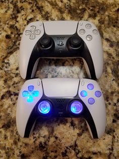 two video game controllers sitting next to each other on top of a marble countertop