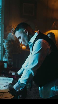 a man standing in front of a desk with papers on it and looking at something