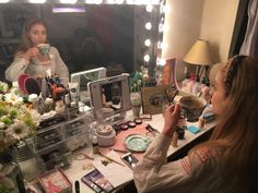 a woman sitting in front of a mirror holding a cup