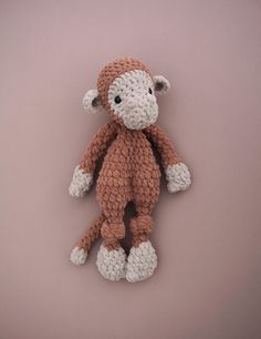 a crocheted stuffed monkey on a pink background