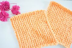 two crocheted dishcloths on a white surface next to pink pom - poms