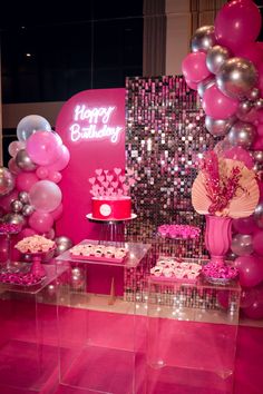 a pink and silver birthday party with balloons, cake and cupcakes on display