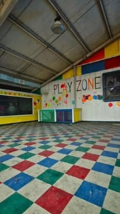 an empty play zone with checkered floor and colorful painted tiles on the walls,