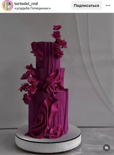 a three tiered purple cake with flowers on top