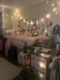 a bedroom with lots of plants on the floor and lights strung from the ceiling above it