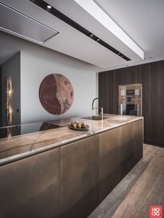 a modern kitchen with marble counter tops and stainless steel appliances, along with an art work on the wall