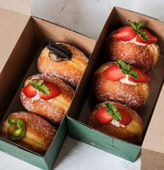 two boxes filled with doughnuts covered in strawberries and topped with powdered sugar