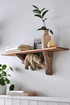 a bear figurine sitting on top of a wooden shelf next to a potted plant