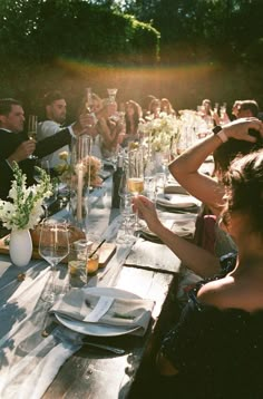 a group of people sitting at a long table with plates and wine glasses on it