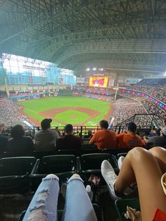 people are sitting in the stands watching a baseball game at an indoor stadium or arena