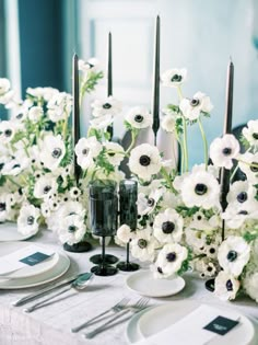 the table is set with white flowers and black candles