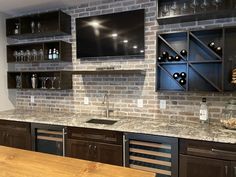 a kitchen counter with wine glasses and bottles on the shelves above it, next to an entertainment center