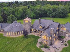 an aerial view of a large stone house in the middle of a lush green field