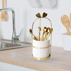 a cup with spoons in it sitting on a counter next to utensils