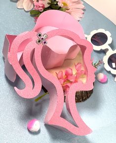 a pink paper cut out of the shape of a woman's head with sunglasses and flowers