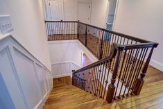 an empty staircase with wooden handrails and white walls in a home's entryway