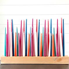 several colored candles are placed in a wooden holder