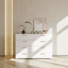 an empty room with a white dresser and potted plant