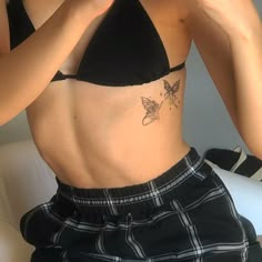 a woman with a butterfly tattoo on her stomach is taking a selfie in the mirror