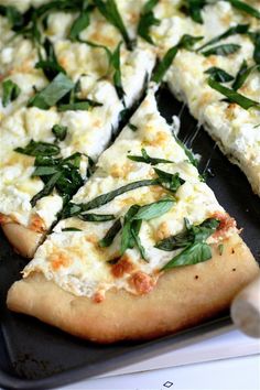 a close up of a pizza on a pan with cheese and green leaves in it