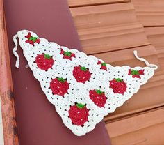 a crocheted strawberry dishcloth hanging on a wooden bench