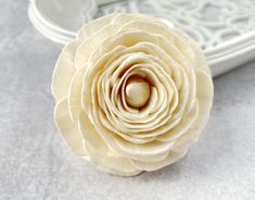 a white flower sitting on top of a table next to a tray with an object in the background