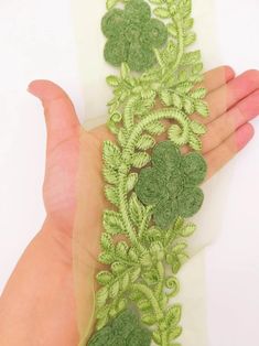 a hand is holding a green lace with flowers on it