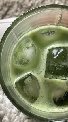 a blender filled with green liquid and ice cubes