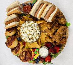 a platter filled with hot dogs, chips, fruit and condiments