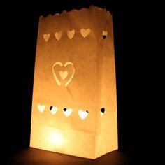 a paper bag with hearts on it in the dark, lit up by a candle