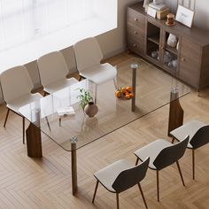 a glass dining table with four chairs and a vase filled with oranges on top