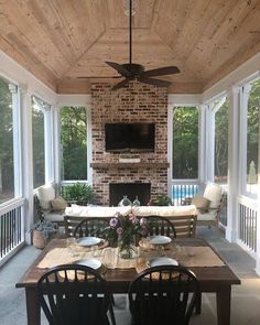 a covered patio with table, chairs and television on the wall in front of an outdoor fireplace