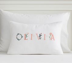 a white pillow with the word livva written in pink and blue flowers on it