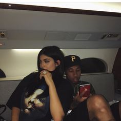 two people sitting on an airplane looking at their phones