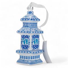 a blue and white candle with a ribbon around it on a white background, in the shape of a pagoda