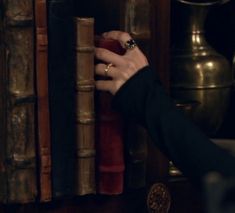 a woman is holding onto an old bookcase in front of a clock and other antique books