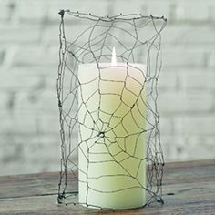 a candle that is sitting on top of a table with a wire net around it