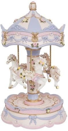 a carousel with three horses on it and pink, blue, and white trimmings