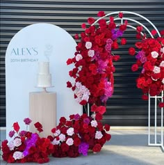 red and pink flowers on display next to a white cake