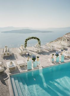 an outdoor pool with chairs and flowers on the side next to it is surrounded by water