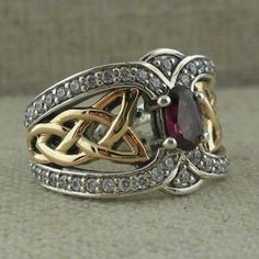 Celtic Knot Ring in Sterling Silver with 10K Gold White Topaz Trim & Rhodolite or Iolite Gem. 13 mm at widest point tapers to 3 mm Gem: Oval 6 mm long 5 mm wide Size 5 to 11 Stamped .925 & 10K Nicely boxed with silver cloth. Rhodolite is Red Iolite is Blue/Purple Spinner Rings Womens, Celtic Knot Wedding Ring, Celtic Knot Wedding, Celtic Wedding Bands, Heart Wedding Rings, Celtic Ring, Celtic Knot Ring, Celtic Wedding Rings, Rings Women