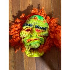 an orange and green mask on top of a wooden floor