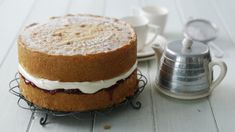 a cake sitting on top of a wire rack next to a cup and saucer