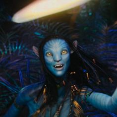 a woman with blue makeup and long hair is in front of an alien like creature