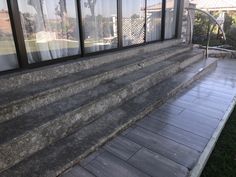 an outside view of a house with stone steps and glass windows that overlook the yard