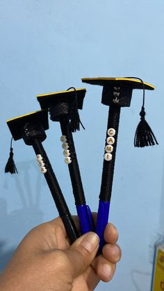 three graduation caps and tassels are held in the palm of a person's hand