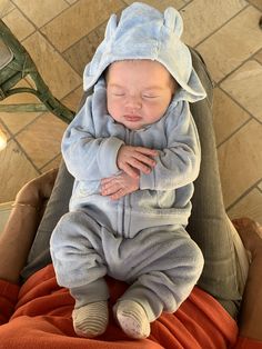 a baby is sleeping in a chair with a towel on it's head and eyes closed