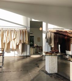 an empty room with clothes hanging on racks and tables in front of the window,